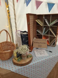 a vintage brown suitcase sits on a table alongside a basket and a log slice with sweet jar and flowers. The case is stood on it's end and had 9 compartments that are filled with cards