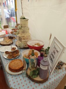 a table strewn with cakes and cupcakes and at the centre is a 3 tiered semi naked cake 