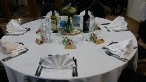 round guest table with fanned napkins, table centre with bottles of wine 